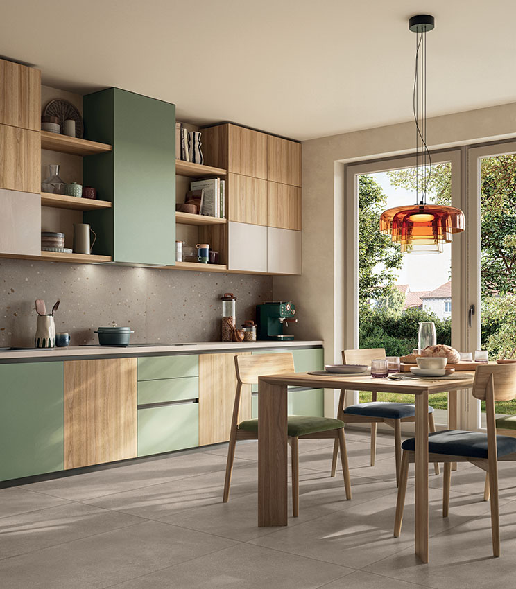 Cuisine moderne et accueillante avec mobilier en bois et vert sauge, coin repas lumineux et sol en grès cérame effet béton aux tons chauds.