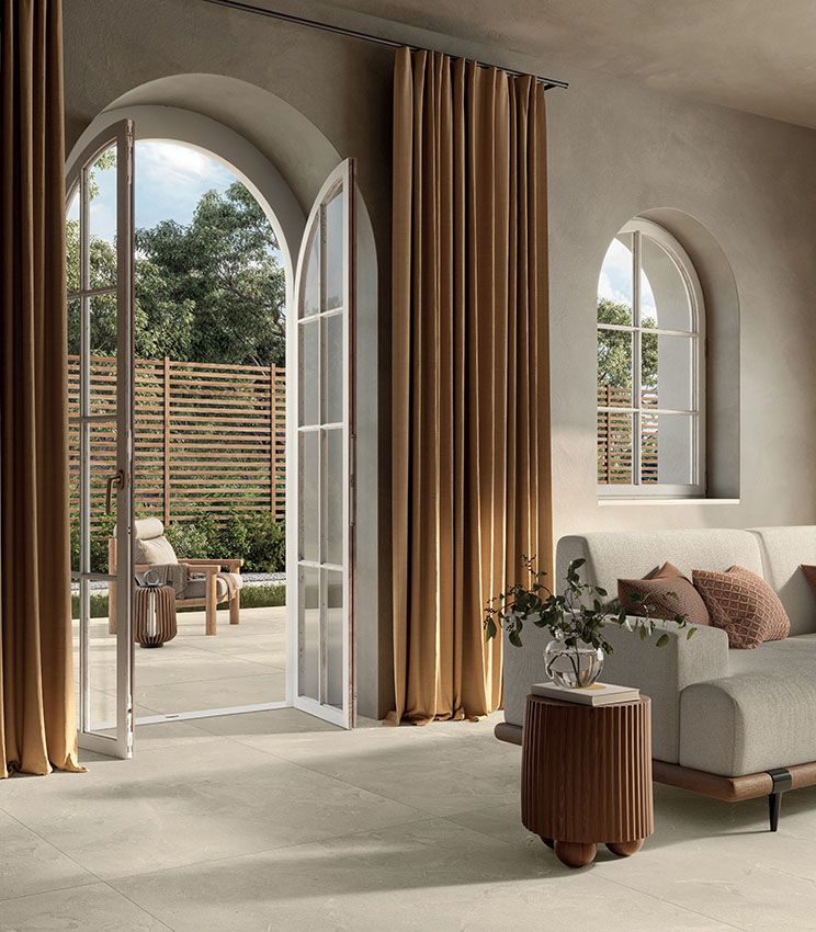 Salon contemporain avec sol en grès cérame effet pierre, tons naturels et larges ouvertures sur l’extérieur pour un espace élégant et lumineux.