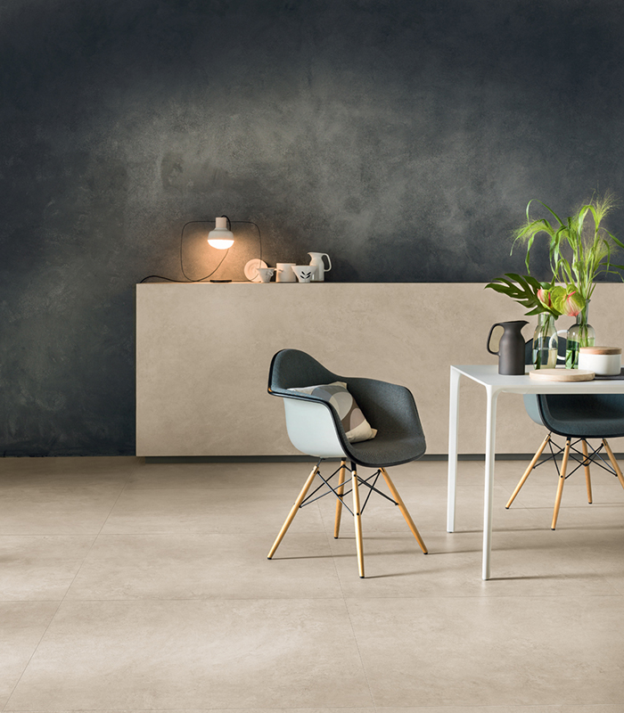 Modern interior with concrete-effect porcelain stoneware flooring, dark walls, and minimalist Nordic-style furnishings.