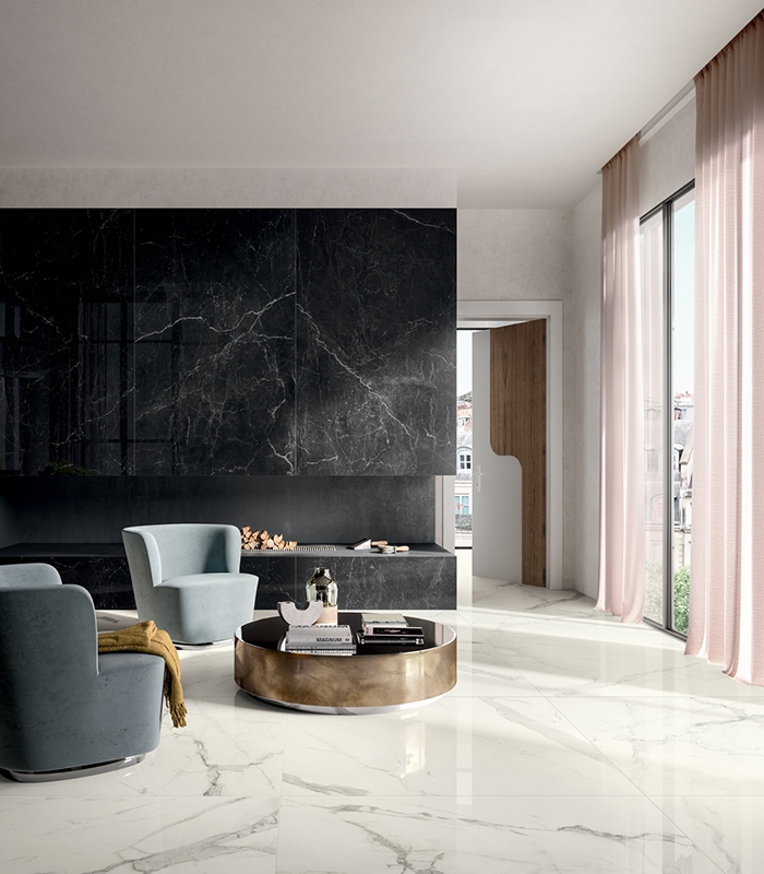 Elegant living room with a modern fireplace and large glass wall on the right. Flooring and walls in white and black marble-effect porcelain stoneware.