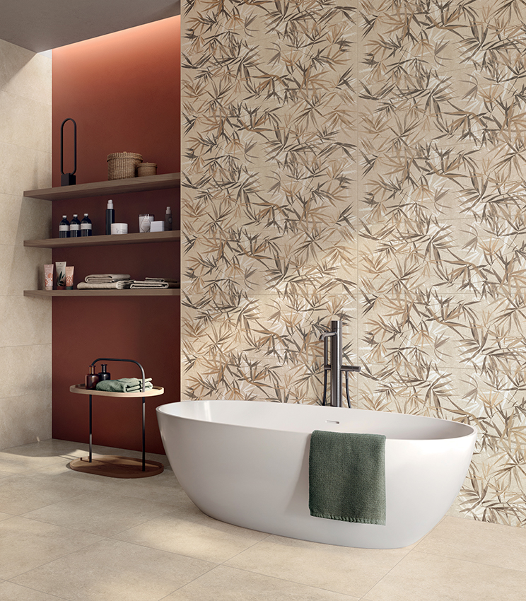 Salle de bains contemporaine avec baignoire îlot, habillée de surfaces de la collection Iqoniqa de Panaria Ceramica : le décor botanique Stalks Warm caractérise le mur principal, associé aux tonalités neutres de Velvet Naturale au sol et sur les murs.