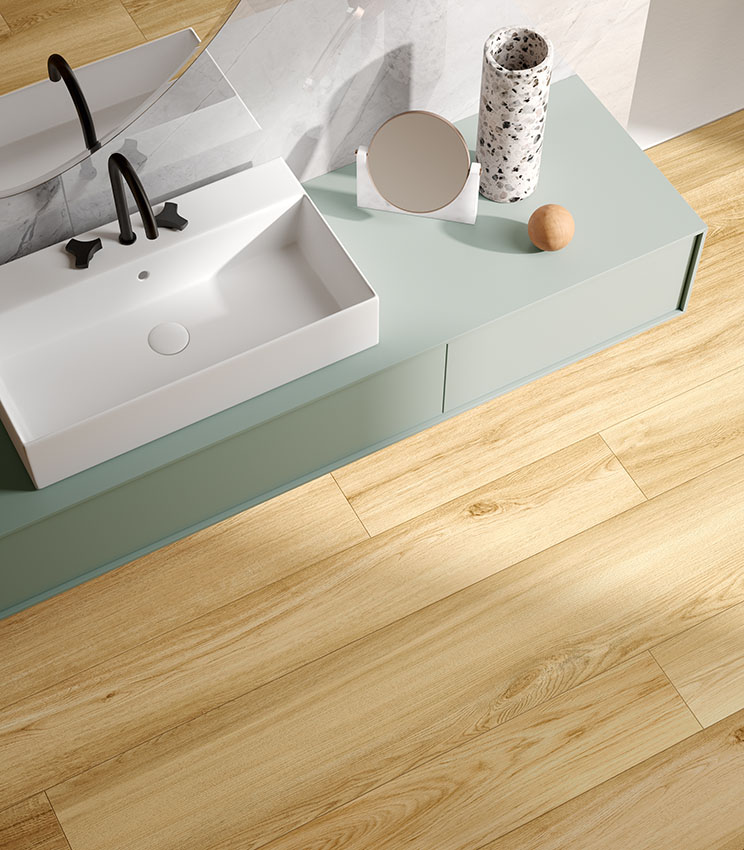 Bagno contemporaneo con pavimento effetto legno chiaro, lavabo bianco e mobile verde salvia, per un ambiente elegante, luminoso e naturale.