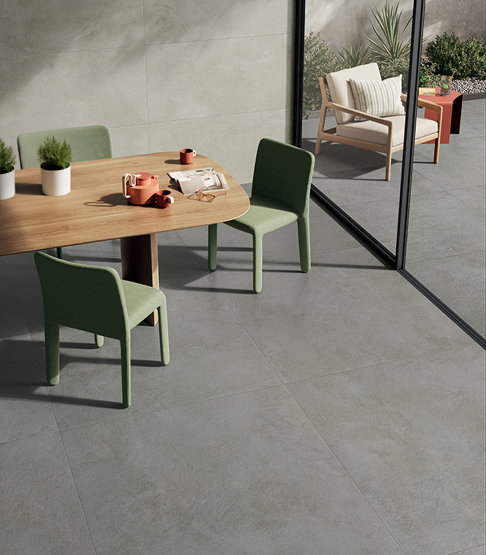Sala da pranzo luminosa con pavimento in gres effetto cemento La Matière di Panaria Ceramica, coordinato con l’outdoor.