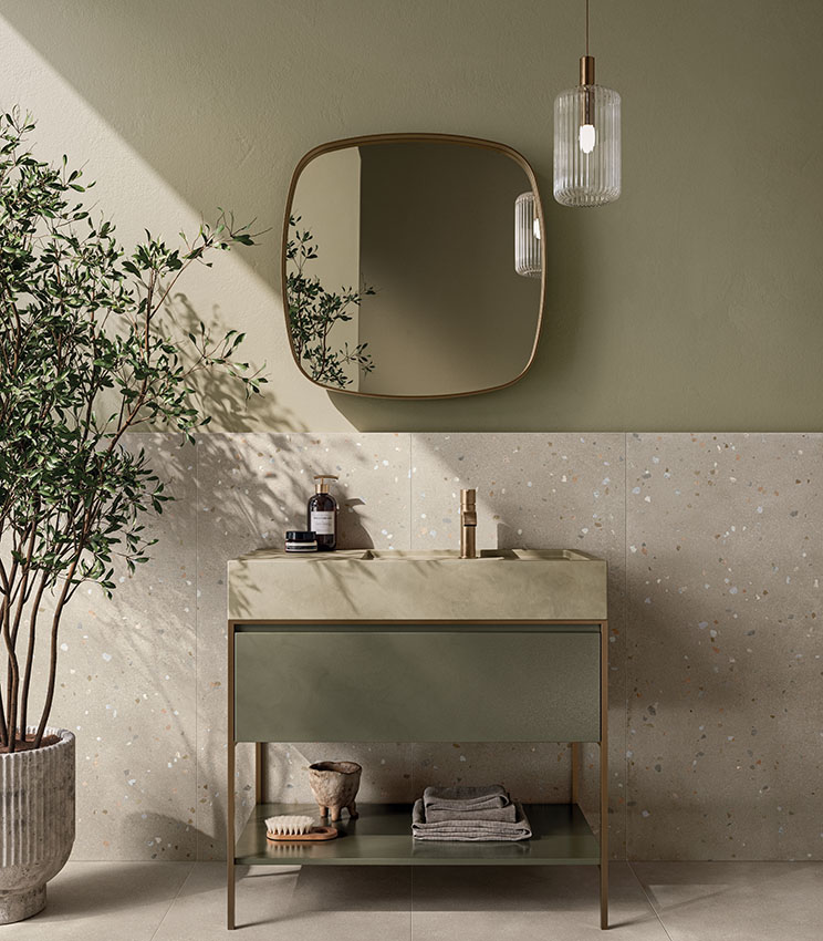 Salle de bains contemporaine avec des surfaces des collections Formula Form Rope et Seed Rope, caractérisée par un revêtement clair ponctué de petits détails colorés, des murs vert sauge, un meuble vasque coordonné, un grand miroir aux formes douces, une suspension et une plante décorative.