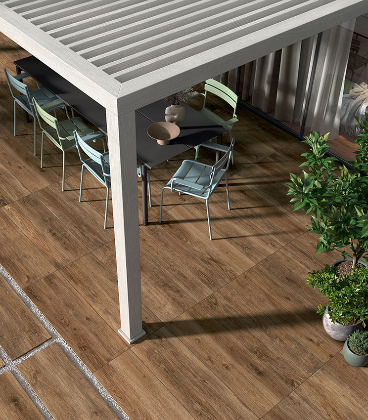 Patio extérieur avec sol en grès cérame effet bois, mobilier contemporain et pergola, pour un espace accueillant, résistant et à l’aspect naturel.