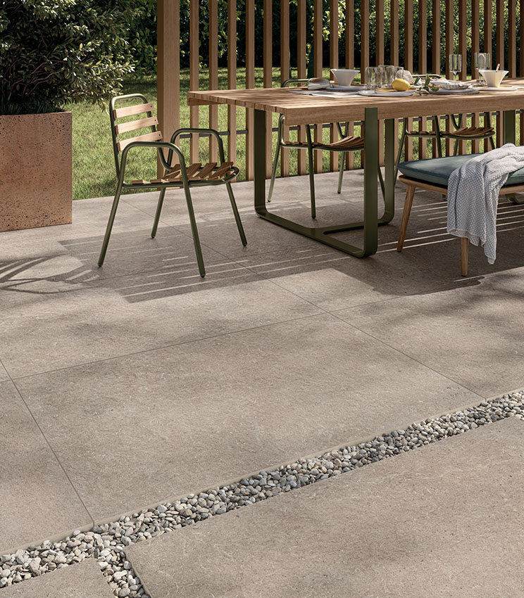 Vue d'un patio de petit-déjeuner revêtu de grès cérame extérieur 20 mm effet pierre couleur sable, posé en partie avec colle et en partie à sec sur gravier | Collection Surround de Panaria Ceramica