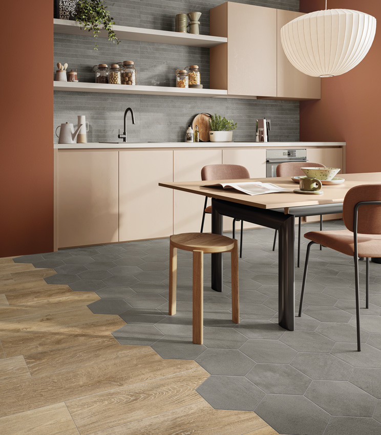 Vue d'une cuisine moderne aux murs peints couleur brique et aux meubles rose poudré, une crédence en listels de grès cérame effet béton gris et un sol multi-effets associant carreaux hexagonaux en céramique effet béton et lames en grès cérame effet bois.