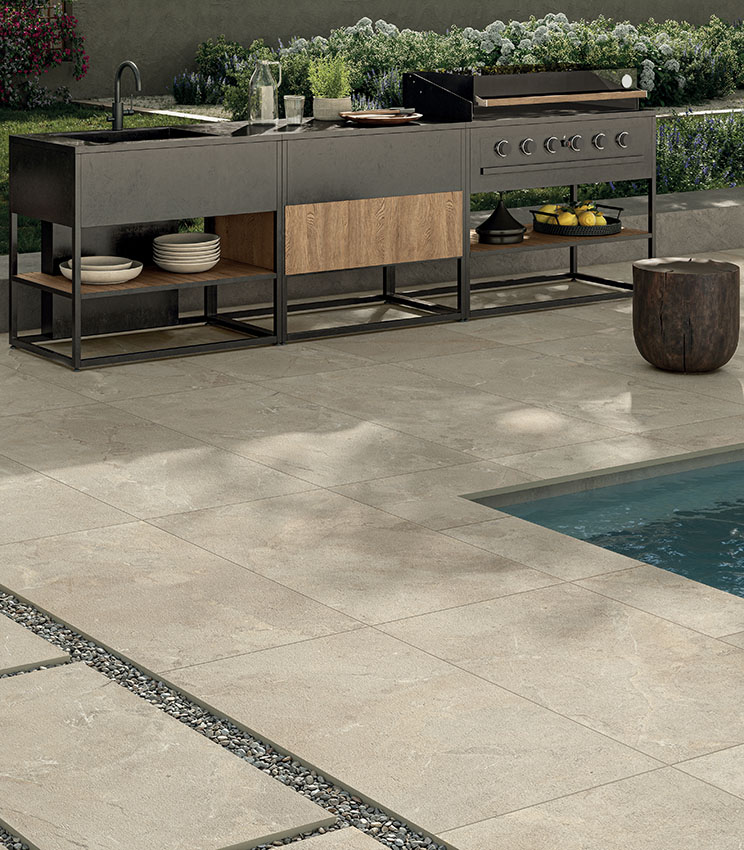 Espace piscine avec sol en grès cérame effet pierre, cuisine extérieure et mobilier contemporain, pour un environnement élégant, résistant et fonctionnel.