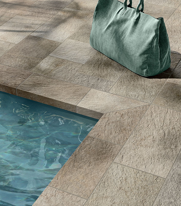 Détail d’un bord de piscine revêtu de grès cérame effet pierre, avec une texture matière et des tons naturels pour un résultat élégant et résistant.
